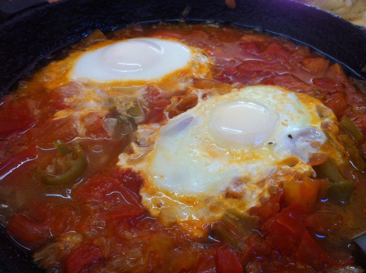 Shakshuka in a cast-iron pan — eggs poached in tomato and pepper sauce